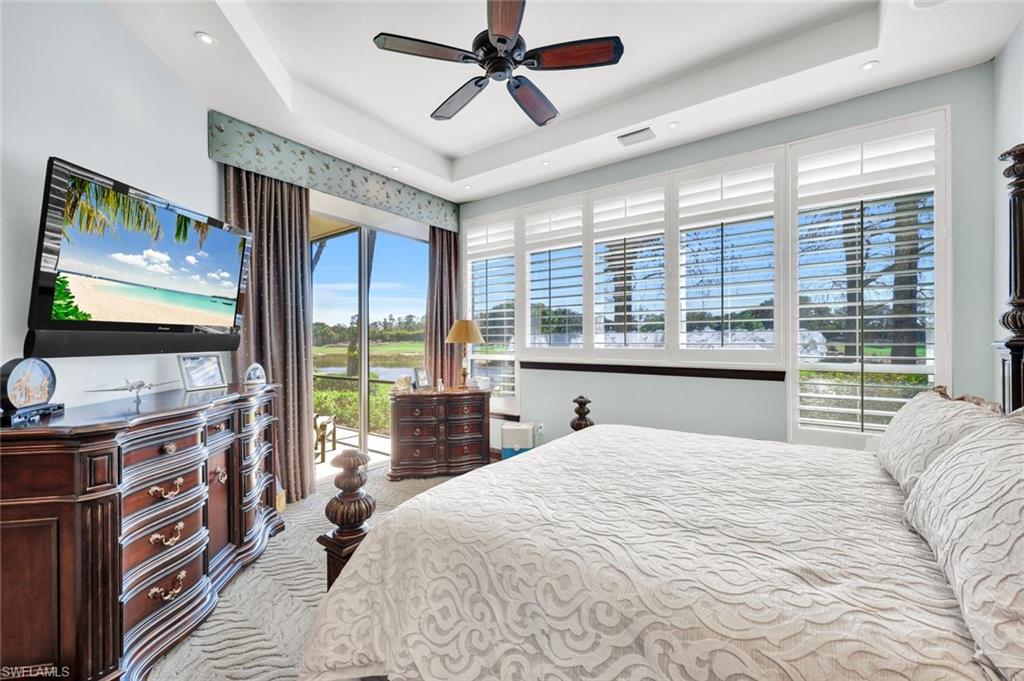 15516 Monterosso Lane, Unit 101 Naples, FL 34110 - Photo 16 of 31 Bedroom featuring access to exterior, a ceiling fan, light carpet, and a tray ceiling