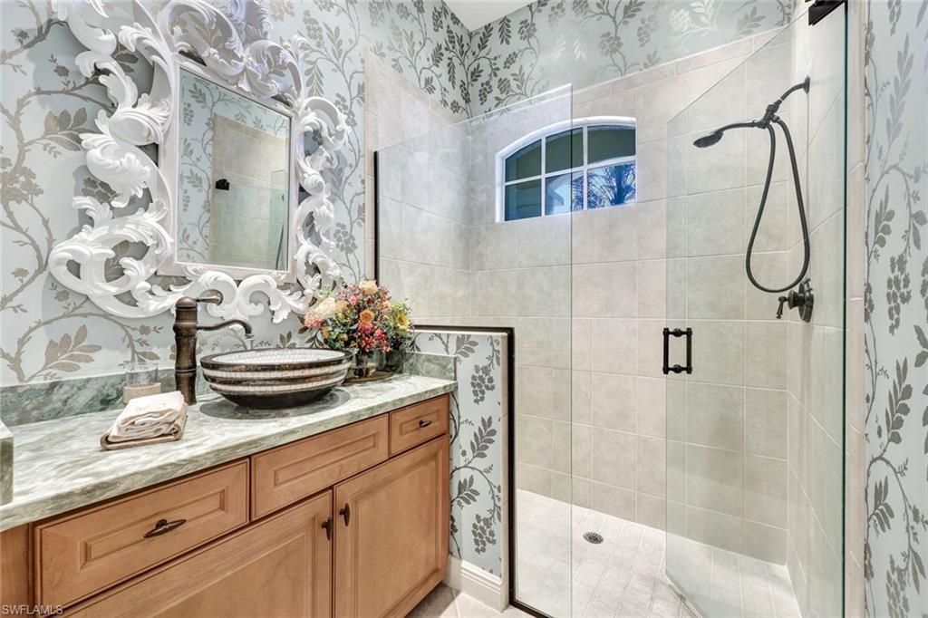 15516 Monterosso Lane, Unit 101 Naples, FL 34110 - Photo 22 of 31 Full bathroom featuring vanity, wallpapered walls, and a stall shower