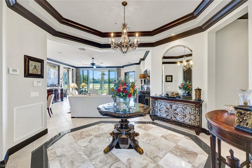 15516 Monterosso Lane, Unit 101 Naples, FL 34110 - Photo 6 of 31 Entryway with ceiling fan, suspended lighting, inlaid floor details, a tray ceiling, and ornamental molding