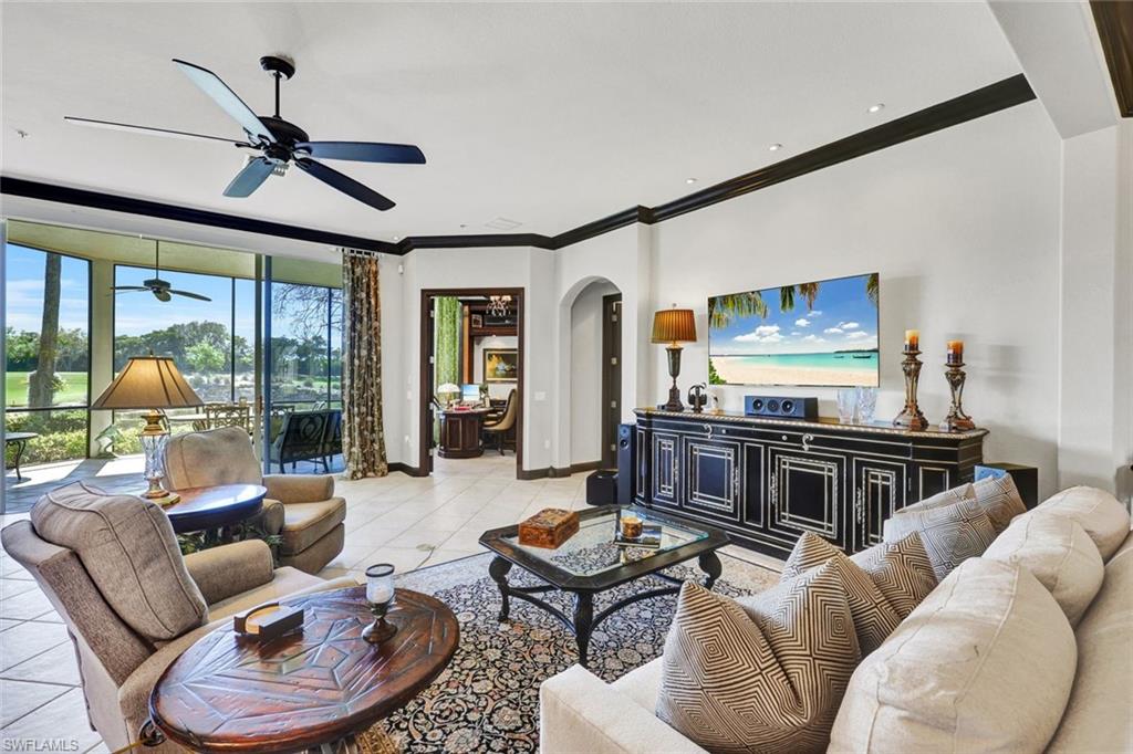 15516 Monterosso Lane, Unit 101 Naples, FL 34110 - Photo 7 of 31 Living room featuring arched walkways, a ceiling fan, crown molding, and light tile patterned floors