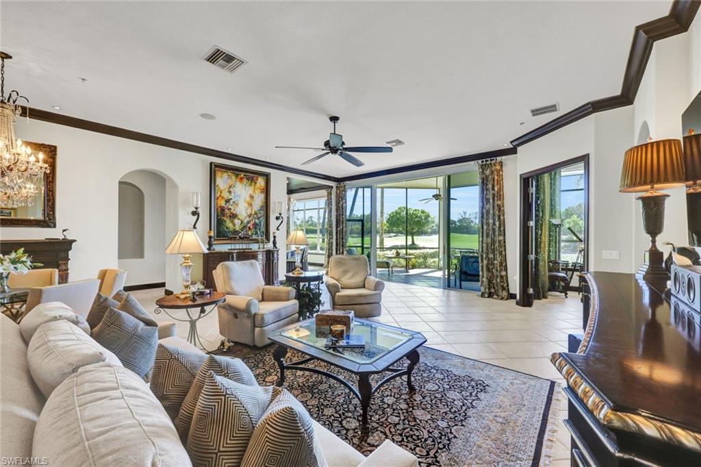 15516 Monterosso Lane, Unit 101 Naples, FL 34110 - Photo 8 of 31 Living room with arched walkways, a ceiling fan, crown molding, light tile patterned floors, and hanging lights