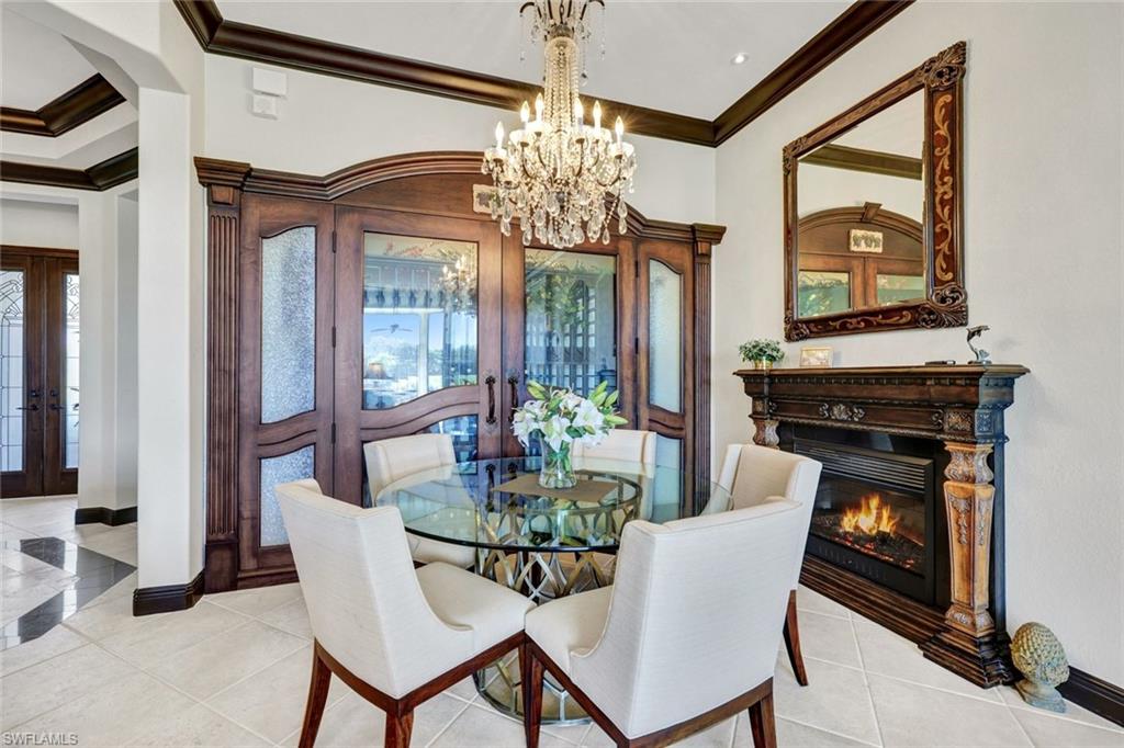 15516 Monterosso Lane, Unit 101 Naples, FL 34110 - Photo 9 of 31 Dining room featuring french doors, crown molding, hanging lights, light tile patterned flooring, and a glass covered fireplace