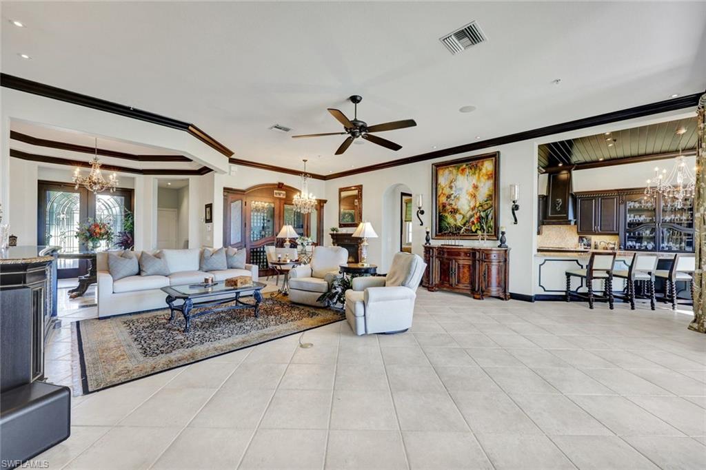 15516 Monterosso Lane, Unit 101 Naples, FL 34110 - Photo 10 of 31 Living room with hanging lights, arched walkways, ornamental molding, and a ceiling fan