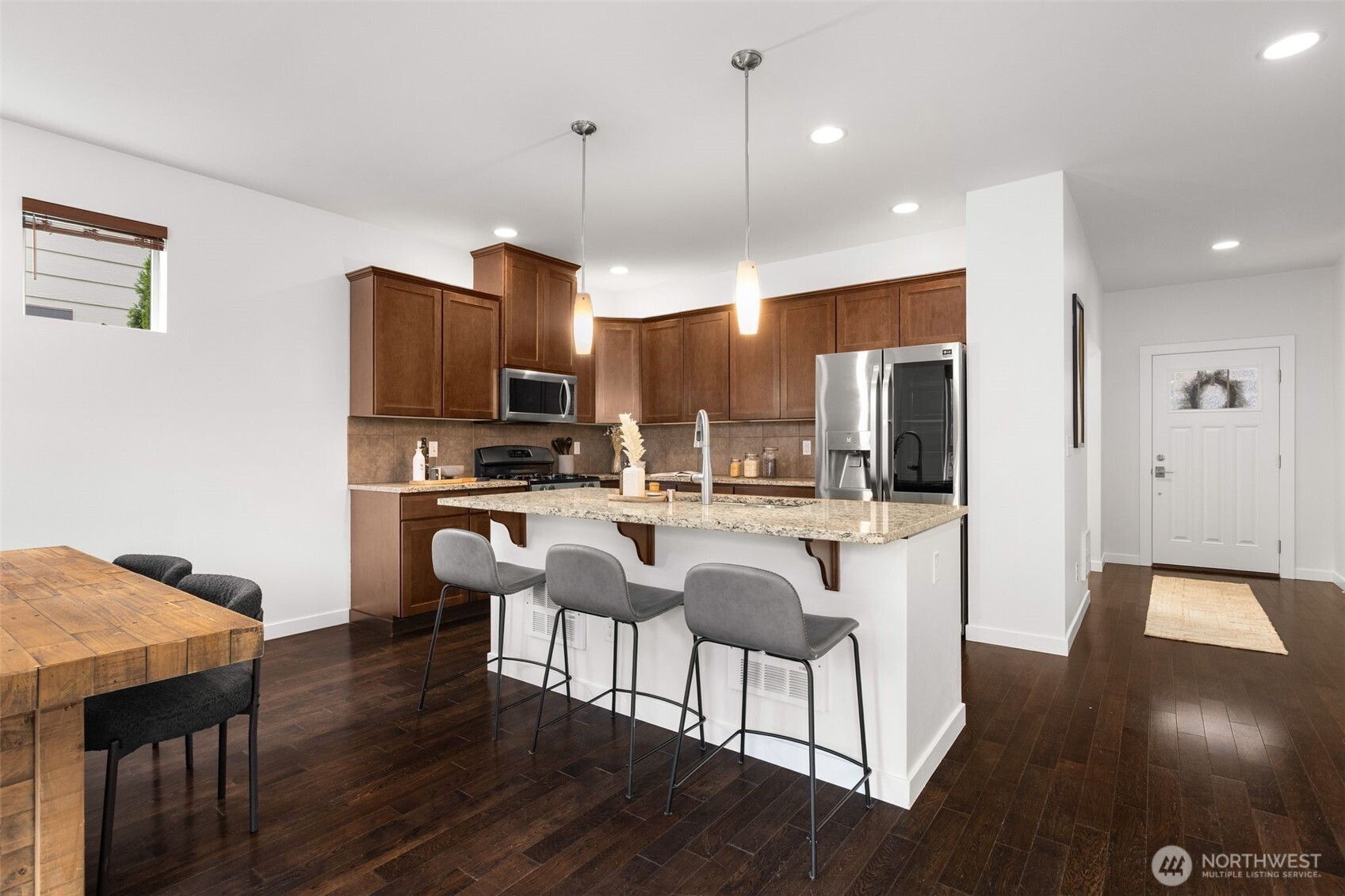 16516 2nd Park Southeast Bothell, WA 98012 - Photo 11 of 39 a kitchen with stainless steel appliances granite countertop a stove top oven a sink dishwasher a refrigerator and a dining table with wooden floor