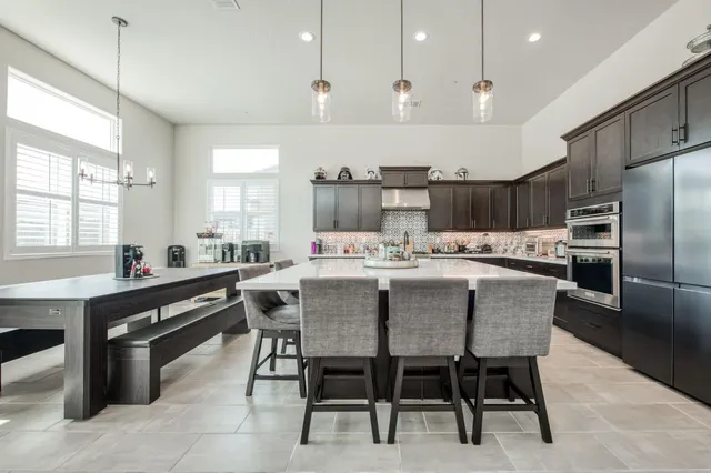a kitchen with kitchen island a dining table chairs and white cabinets