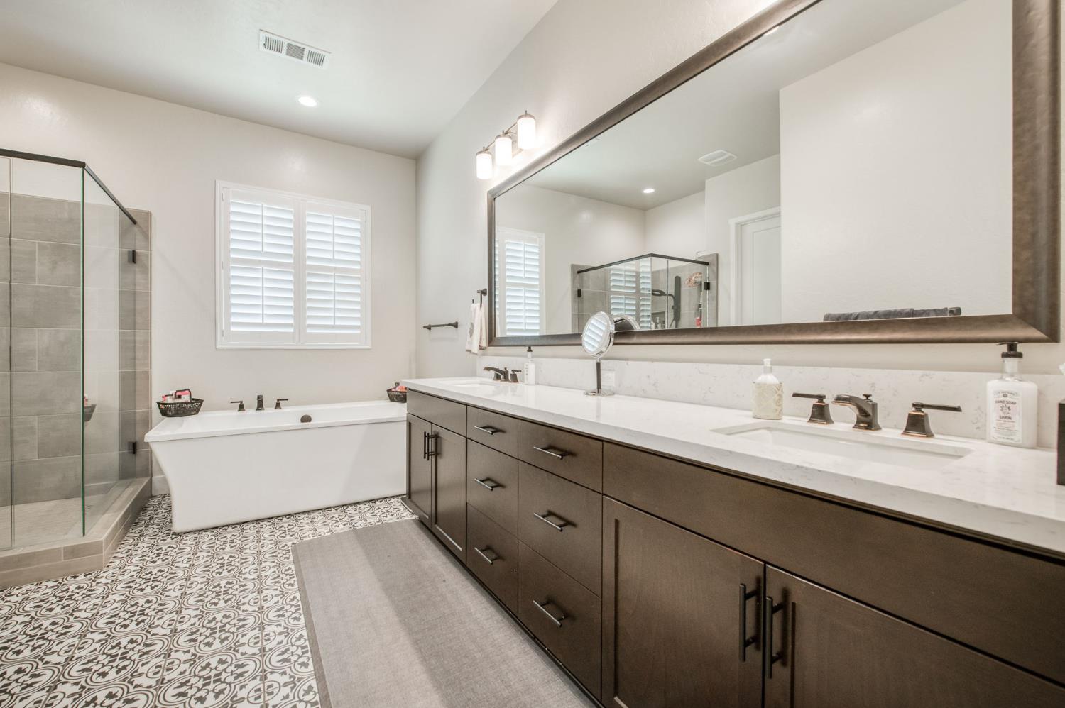 1020 Highland Road Madera, CA 93636 - Photo 19 of 42 a bathroom with a double vanity sink a mirror and a bathtub