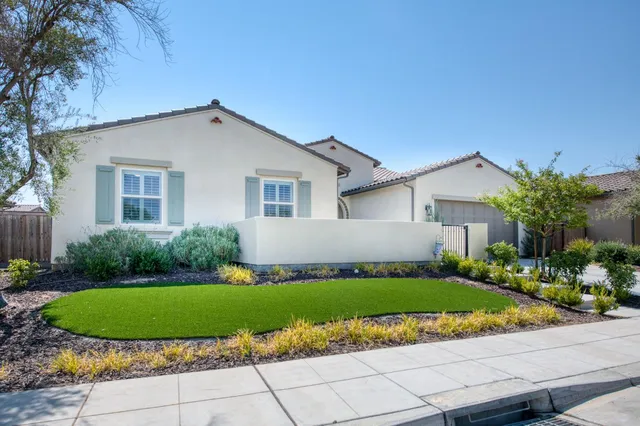 a view of a house with a yard and potted plants