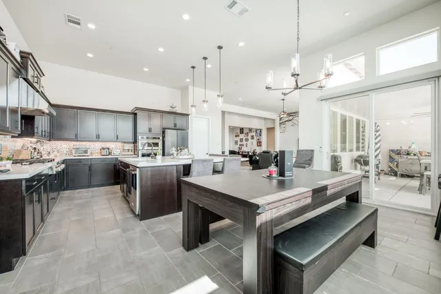 a open kitchen view with stainless steel appliances kitchen island a stove a sink dishwasher a oven and a dining table with wooden floor