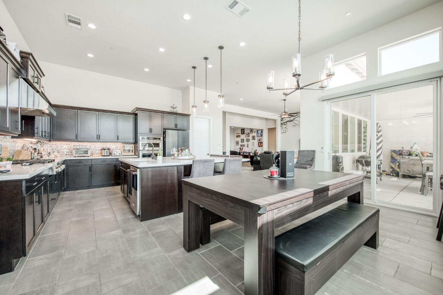 1020 Highland Road Madera, CA 93636 - Photo 8 of 42 a open kitchen view with stainless steel appliances kitchen island a stove a sink dishwasher a oven and a dining table with wooden floor