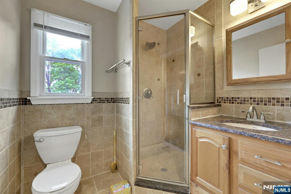 17 Butler Place Wanaque, NJ 07420 - Photo 26 of 28 a bathroom with a granite countertop toilet sink and shower