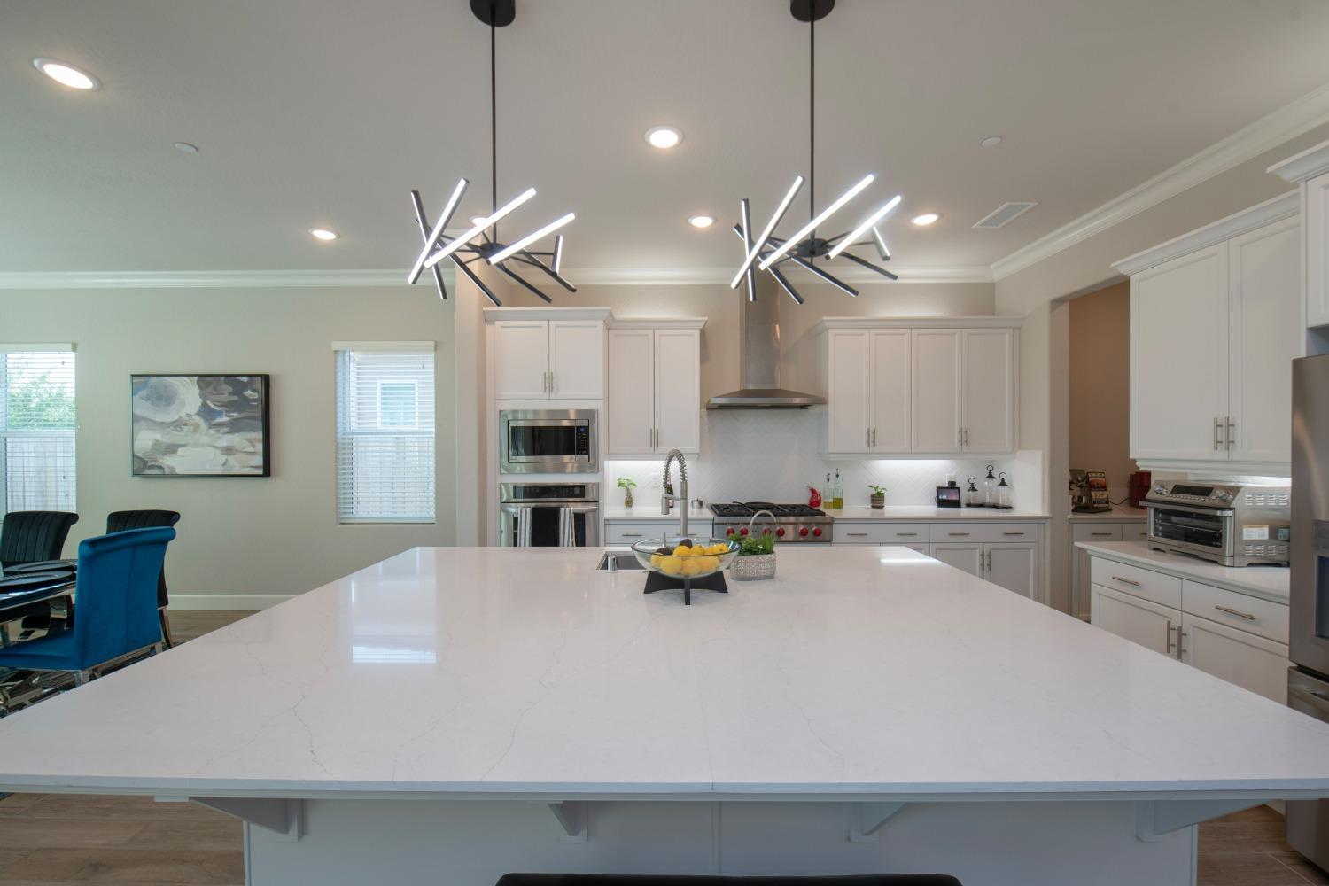 2120 North Perry Avenue Clovis, CA 93619 - Photo 3 of 37 a kitchen with a refrigerator a stove a sink dishwasher a dining table and chairs with wooden floor