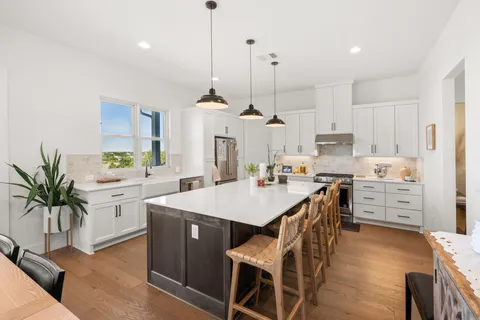 a kitchen with stainless steel appliances kitchen island granite countertop a stove a sink a refrigerator a center island and a window