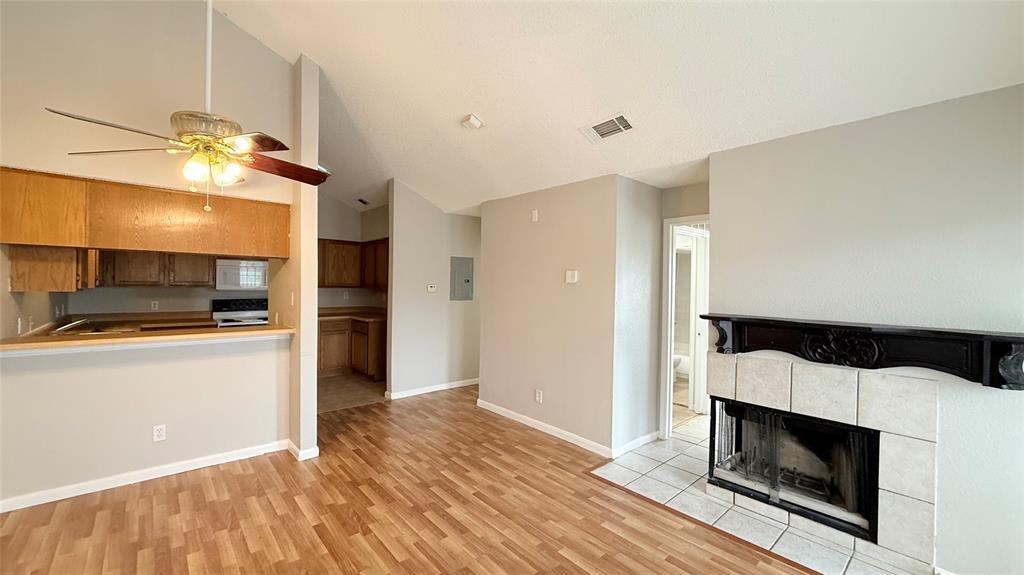 6108 Abrams Road, Unit 125 Dallas, TX 75231 - Photo 9 of 20 Wood-finish flooring, vaulted ceilings, and a fireplace with a decorative mantel and tile surround