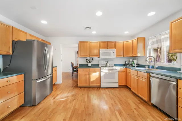 a kitchen with granite countertop wooden floors stainless steel appliances a sink and a window