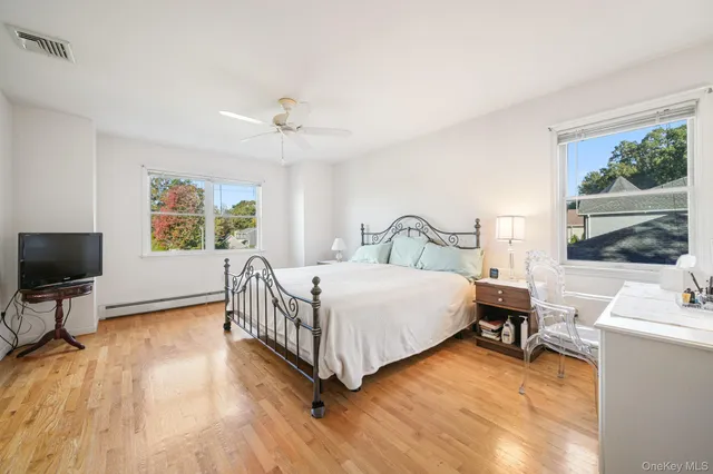 a bedroom with a bed window table chair and television