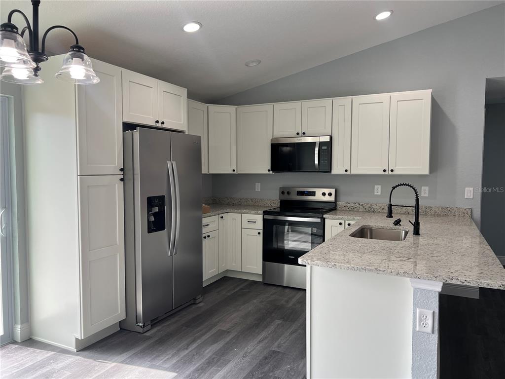 2512 Southwest 147 Place Road Ocala, FL 34473 - Photo 2 of 13 a kitchen with granite countertop a refrigerator stove and microwave
