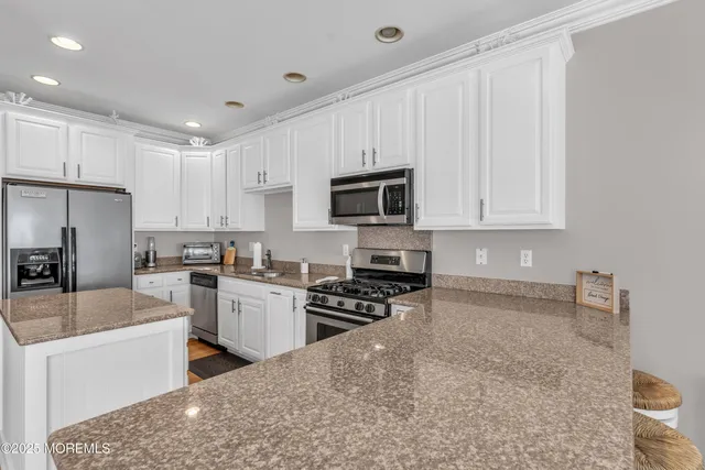 a kitchen with granite countertop a stove sink microwave and refrigerator