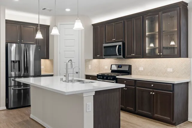 a kitchen with kitchen island granite countertop a stove refrigerator and microwave