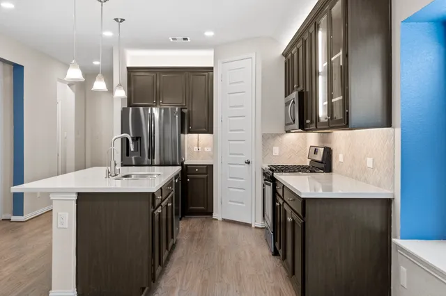 a kitchen with kitchen island a sink stove top oven and refrigerator