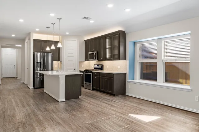 a large kitchen with a large counter top stainless steel appliances and cabinets