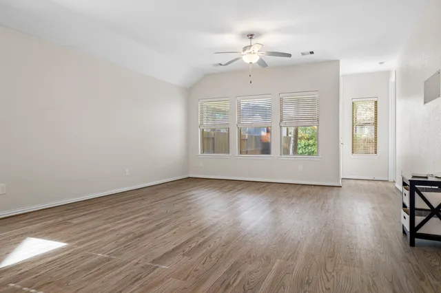 a view of an empty room with wooden floor and a window