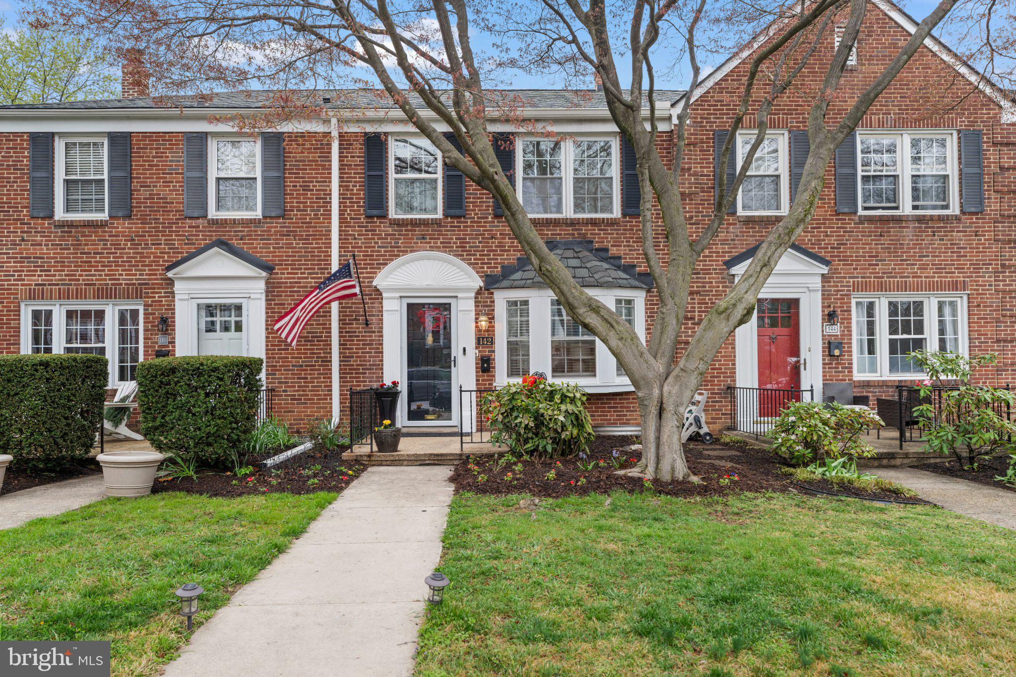 Charming brick townhome with lush greenery.