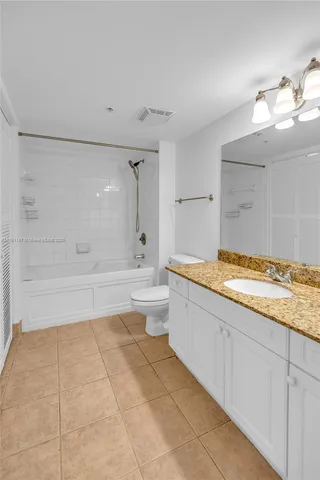 a bathroom with a granite countertop sink a toilet and bathtub