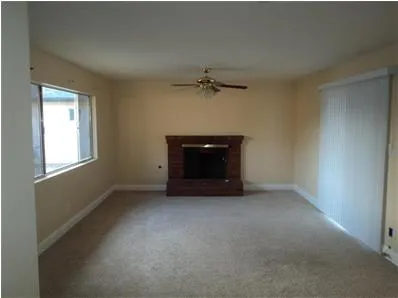an empty room with a fireplace and a ceiling fan