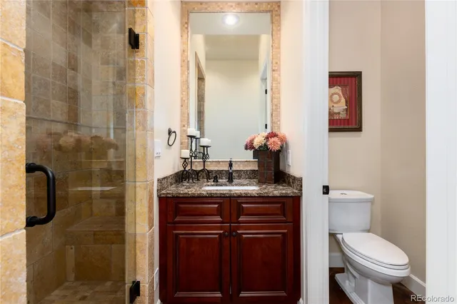 a bathroom with a granite countertop toilet sink and mirror
