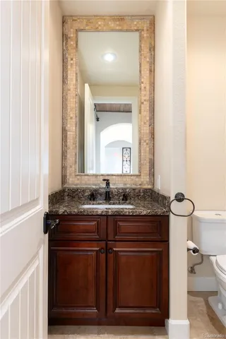 a bathroom with a granite countertop sink a toilet and a mirror