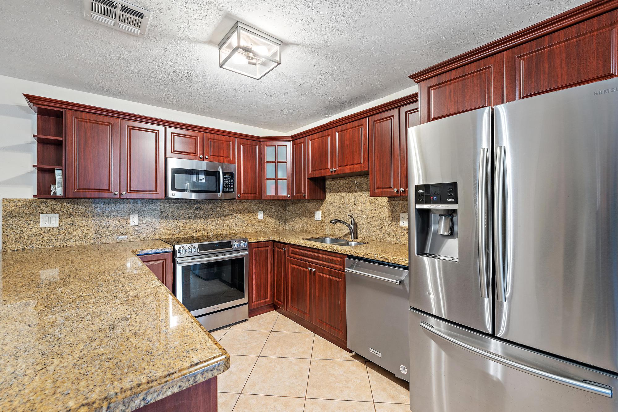 14765 Calusa Trail Palm Beach Gardens, FL 33418 - Photo 14 of 49 a kitchen with stainless steel appliances granite countertop a refrigerator stove top oven and sink