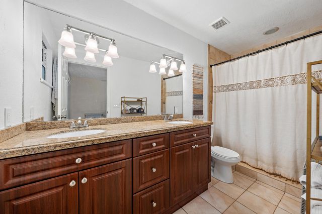a spacious bathroom with a granite countertop sink a toilet and a mirror