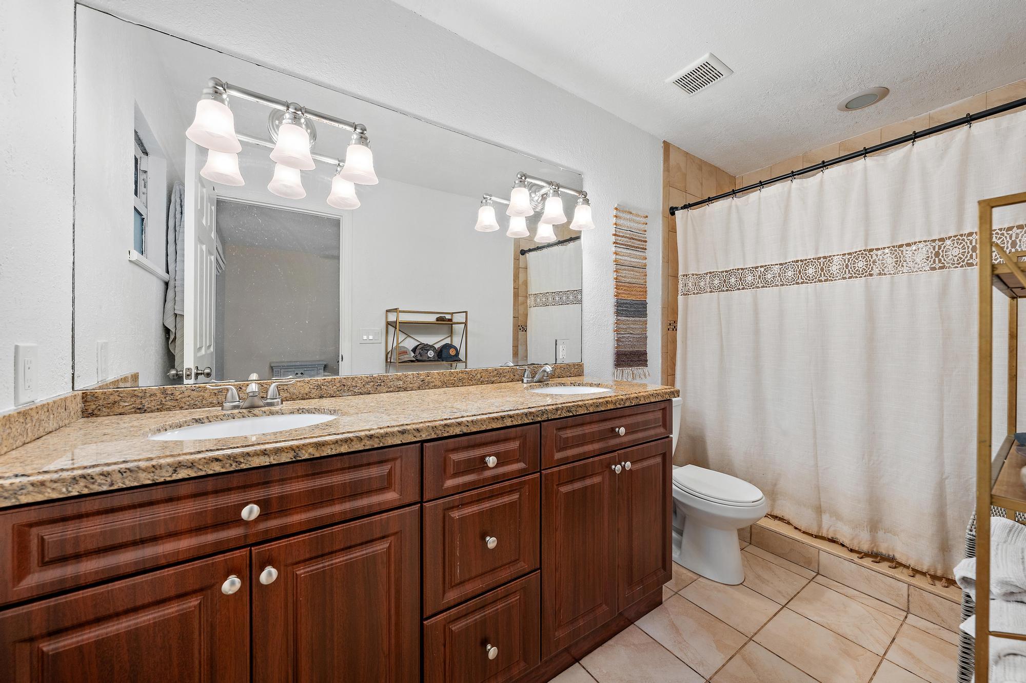 14765 Calusa Trail Palm Beach Gardens, FL 33418 - Photo 17 of 49 a spacious bathroom with a granite countertop sink a toilet and a mirror