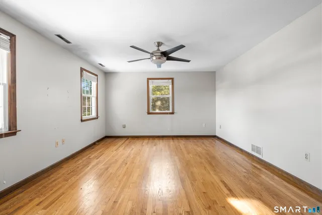 a view of a big room with wooden floor and windows