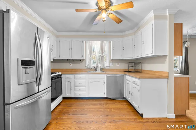 a kitchen with granite countertop a refrigerator a sink a stove and white cabinets