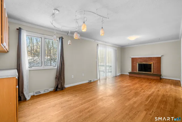 a view of empty room with wooden floor and fireplace