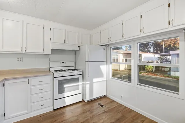a kitchen with granite countertop white cabinets and white appliances