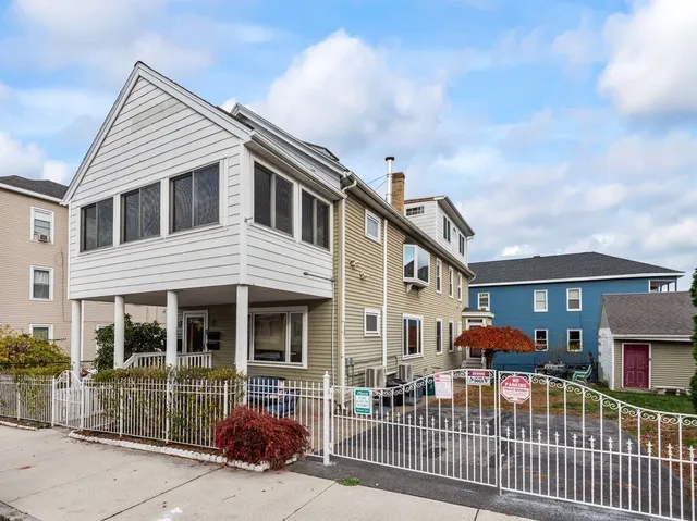 a view of a white house with large windows and a small yard