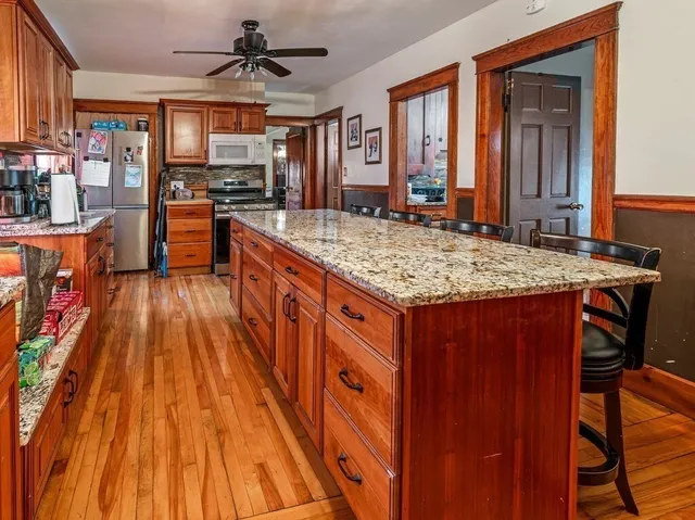 a kitchen with stainless steel appliances granite countertop wooden cabinets a stove a sink and a wooden floors