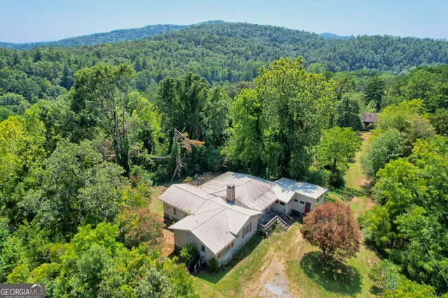 an aerial view of residential house with outdoor space and trees all around