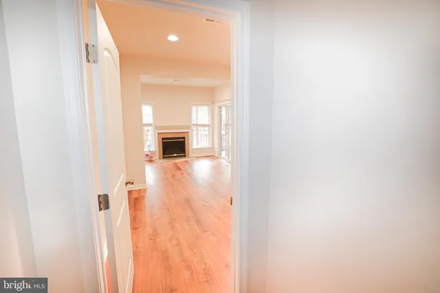 a view of a hallway with wooden floor and a bathroom