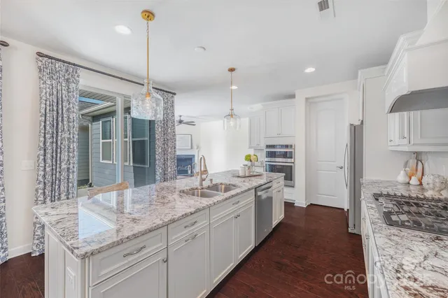 a large kitchen with kitchen island granite countertop a large center island a sink stainless steel appliances and cabinets