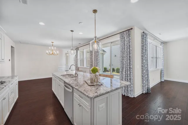 a kitchen with granite countertop a sink appliances and wooden floor