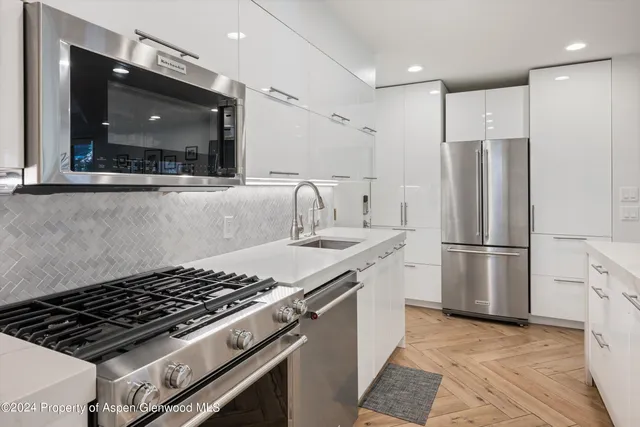 a kitchen with stainless steel appliances granite countertop a sink and a refrigerator