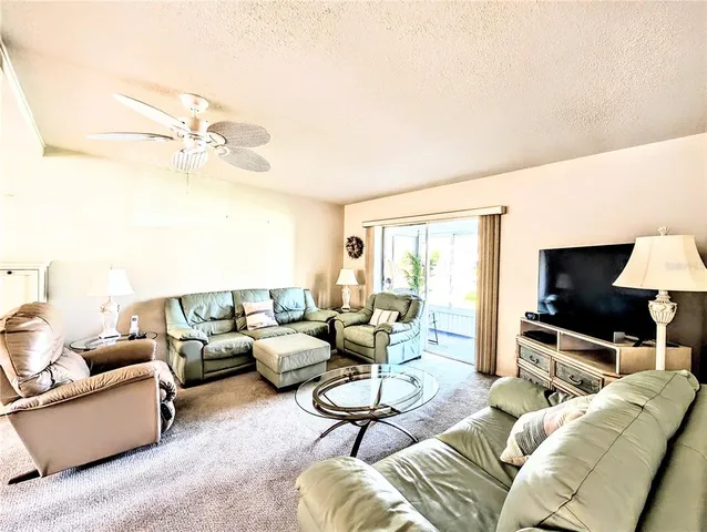 a living room with furniture a ceiling fan and a flat screen tv