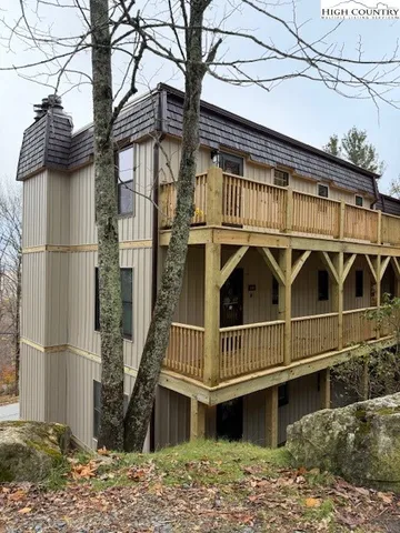 a view of a house with a small yard and large tree