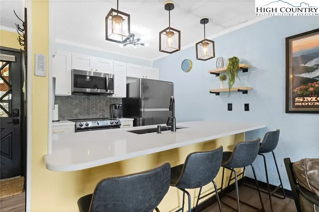 a dining room with wooden floor a chandelier a wooden table and chairs