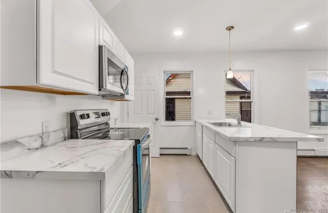 a kitchen that has a lot of white cabinets and stainless steel appliances
