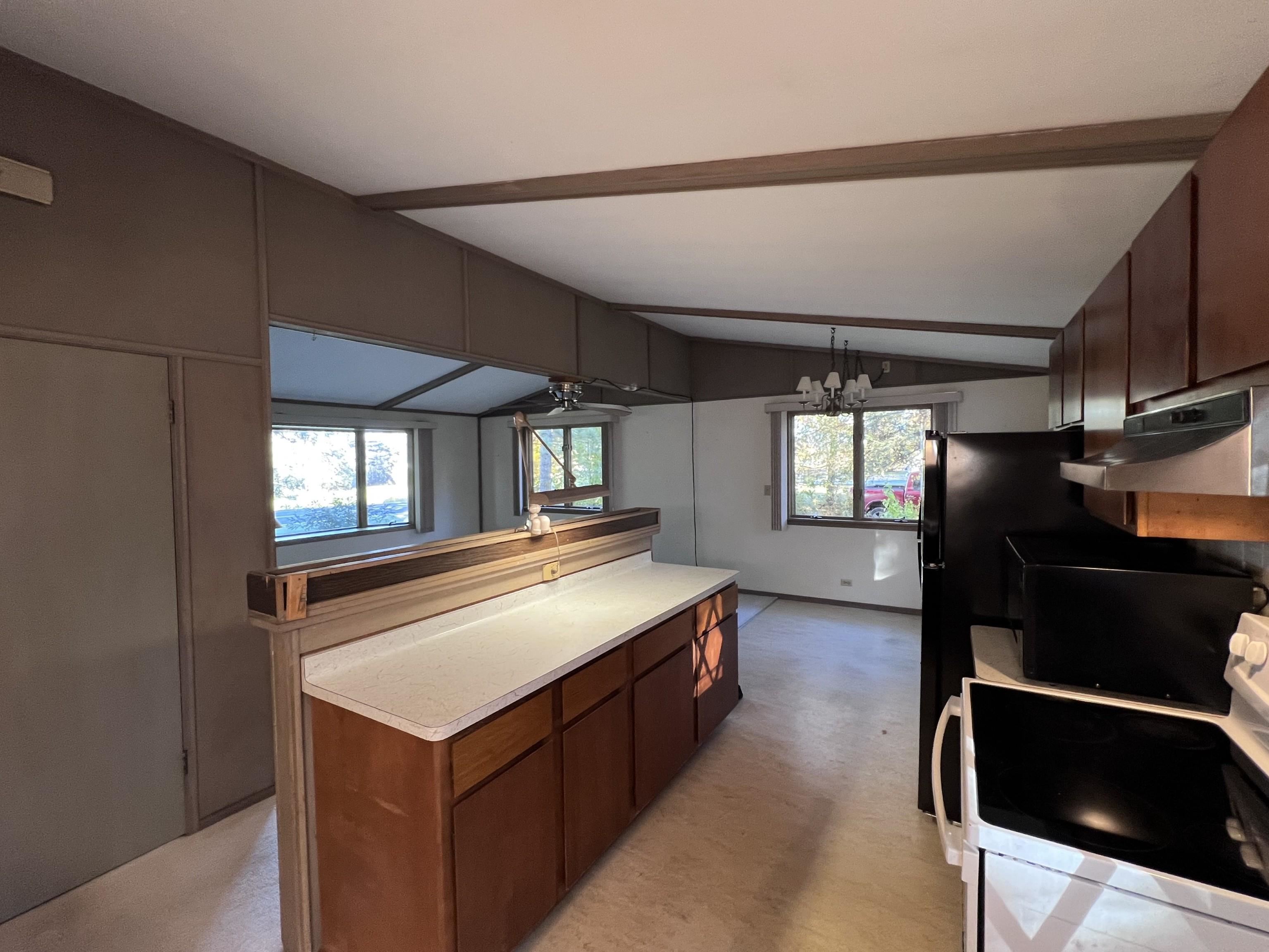 202 North 58th Street Superior, WI 54880 - Photo 10 of 30 Kitchen featuring white electric stove, light countertops, under cabinet range hood, decorative light fixtures, and a chandelier
