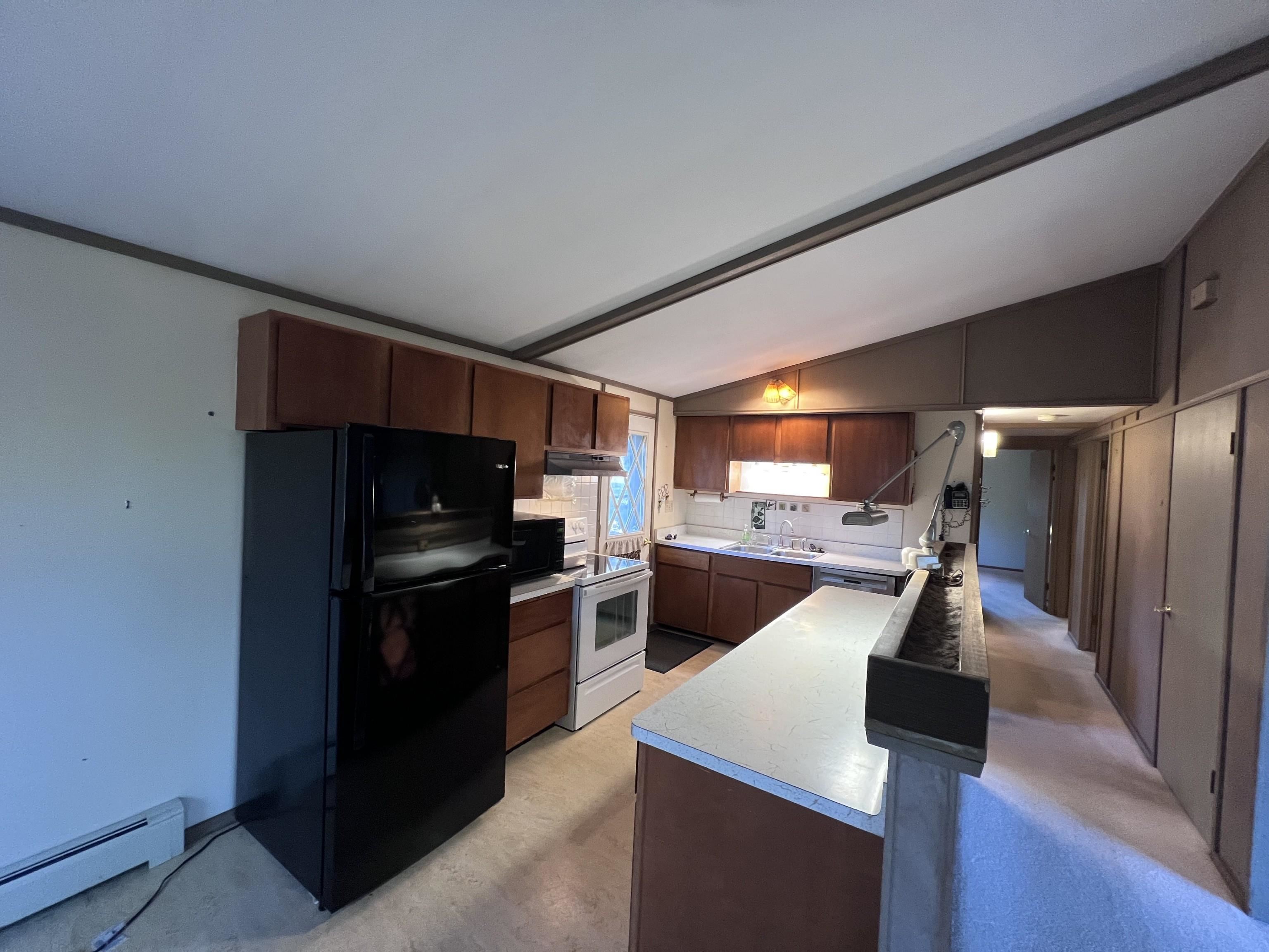 202 North 58th Street Superior, WI 54880 - Photo 11 of 30 Kitchen with black appliances, light countertops, a baseboard heating unit, tasteful backsplash, and under cabinet range hood